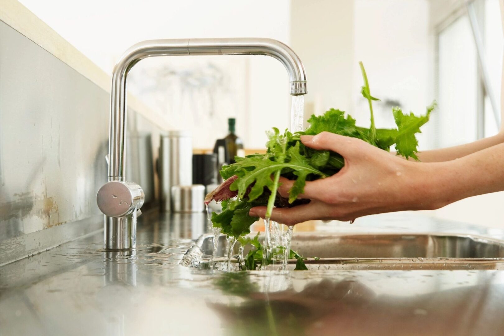 A person washing vegetables in the sink.
