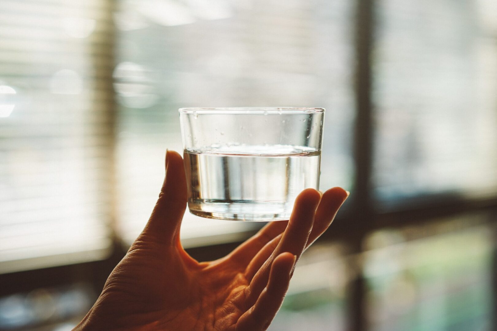A person holding a glass of water in their hand.